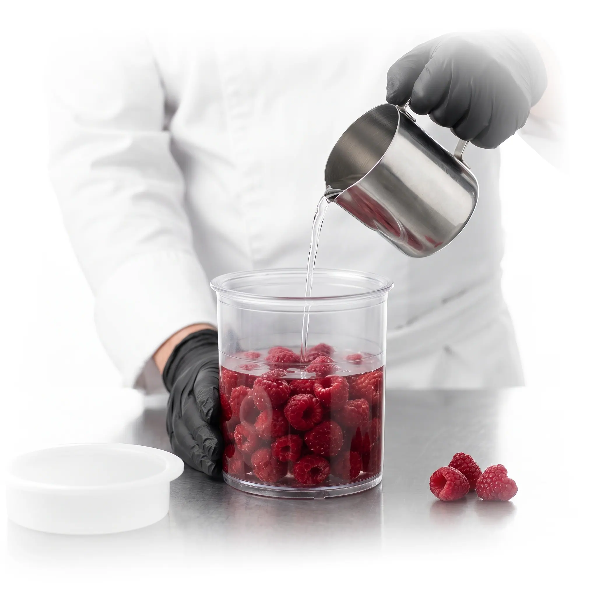 Un chef verse le liquide sur les framboises dans le bol